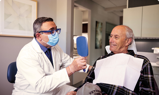 Dentist showing mirror to smiling older patient.