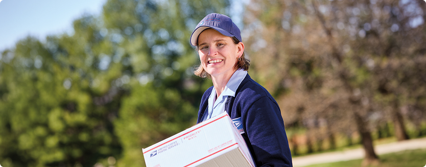  Smiling mail carrier holding package.