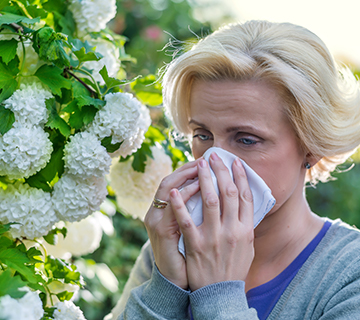 Woman blowing nose near flowers